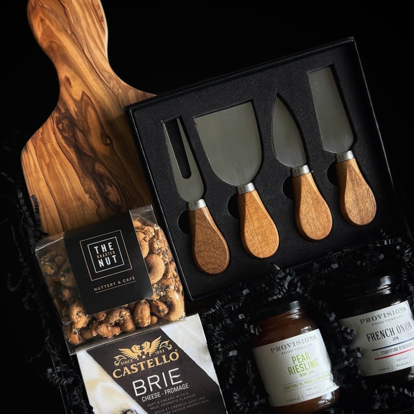 Seasonal Soirée luxury holiday gift box featuring an elegant charcuterie presentation with brie cheese, artisan spreads, gourmet crackers, and cheese knives on a wooden serving board — designed for refined holiday entertaining.