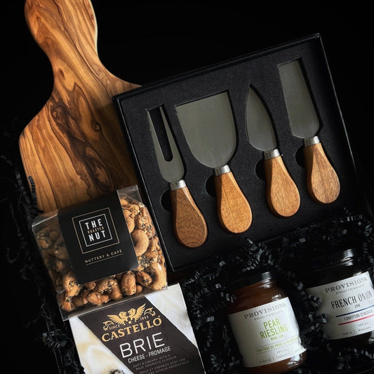 Seasonal Soirée luxury holiday gift box featuring an elegant charcuterie presentation with brie cheese, artisan spreads, gourmet crackers, and cheese knives on a wooden serving board — designed for refined holiday entertaining.