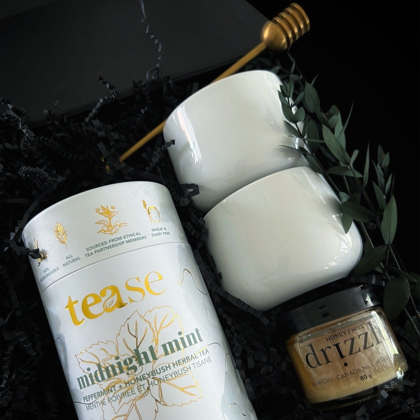 Luxury tea gift box featuring midnight mint tea, porcelain mugs, whipped honey, and a gold honey dipper in elegant black and gold packaging.