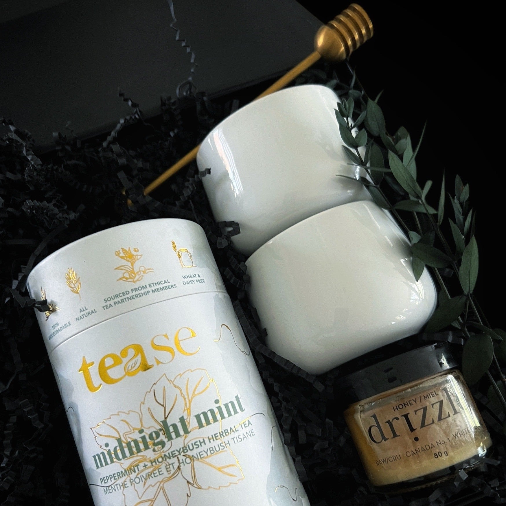 Luxury tea gift box featuring midnight mint tea, porcelain mugs, whipped honey, and a gold honey dipper in elegant black and gold packaging.