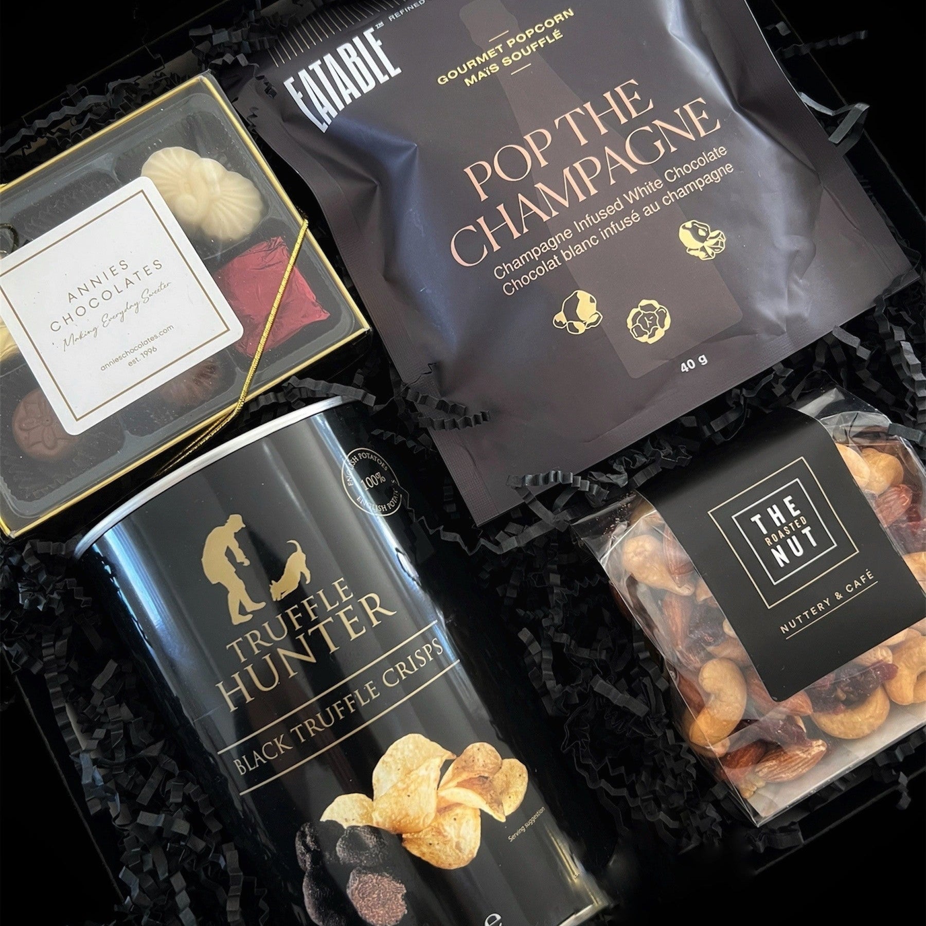 Luxury holiday gift box featuring Canadian-made gourmet treats, including chocolates, truffle crisps, popcorn, and roasted nuts, beautifully packaged for festive gifting.